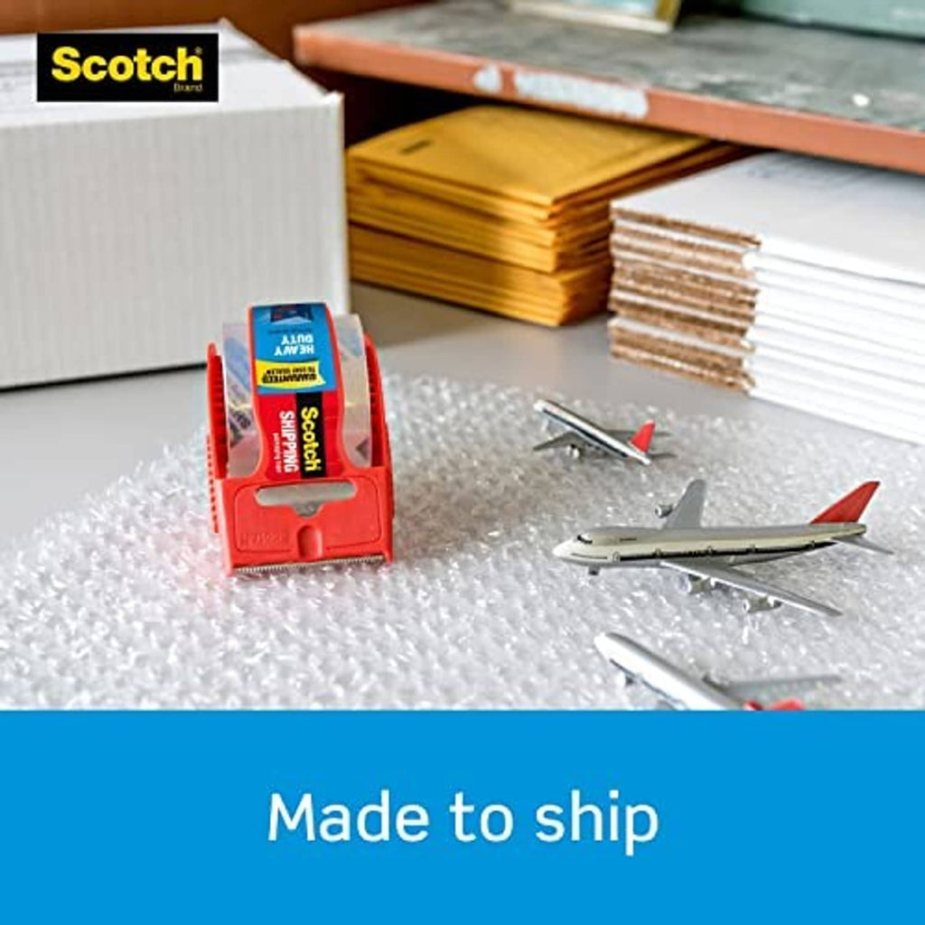 Scotch heavy-duty tape dispenser beside stacked cardboard boxes and envelopes