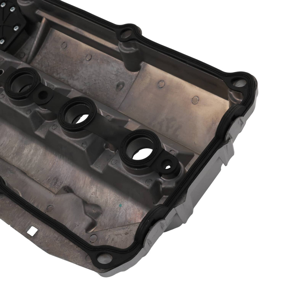 Valve cover interior close-up with oil channels, round ports, and black gasket