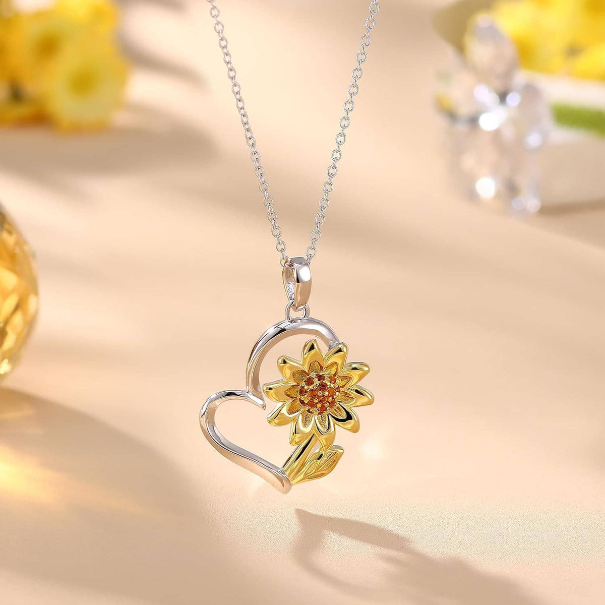 Heart-shaped pendant with gold-plated sunflower and crystal center on a silver chain.
