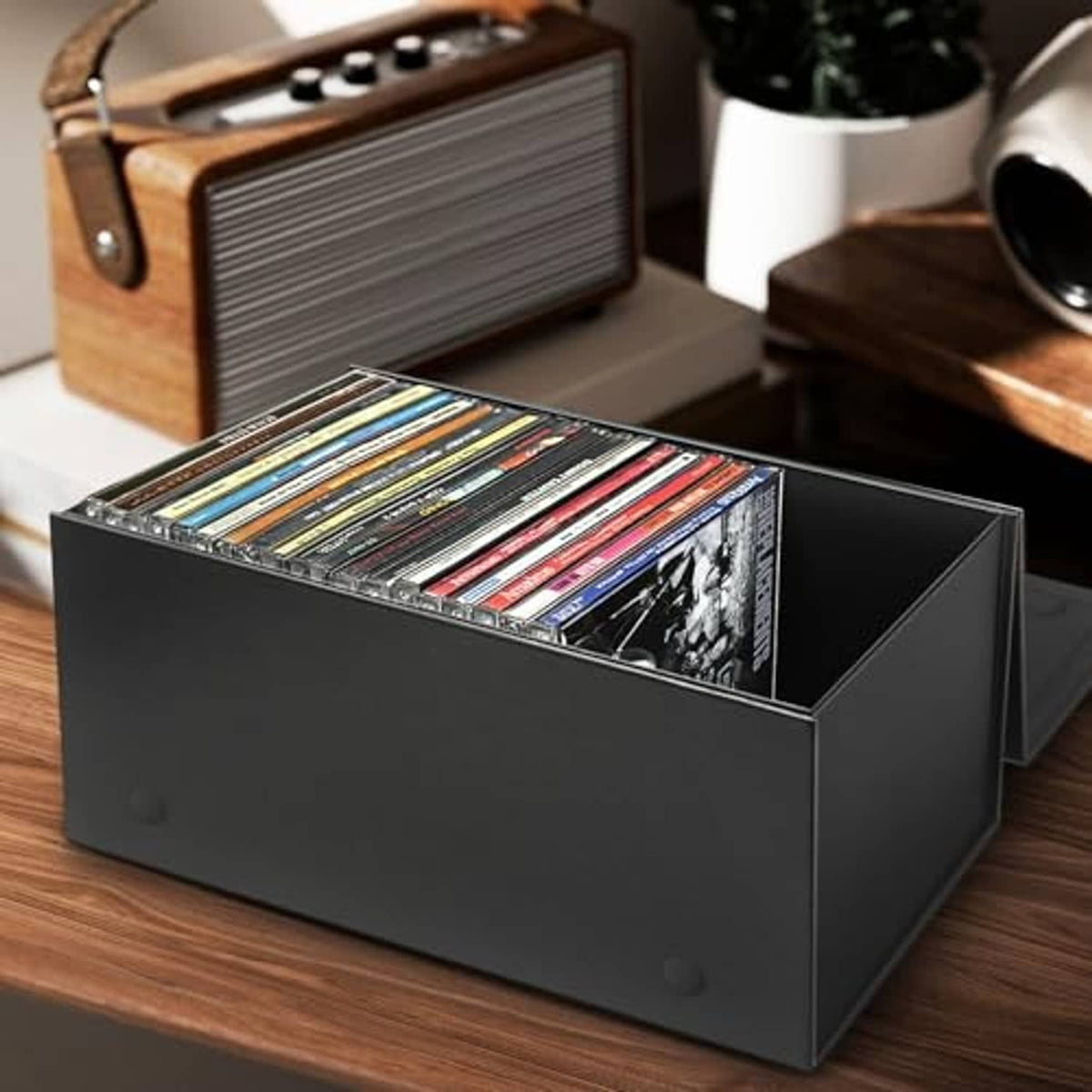 Black CD storage box open on desk, jewel cases visible in the front tray