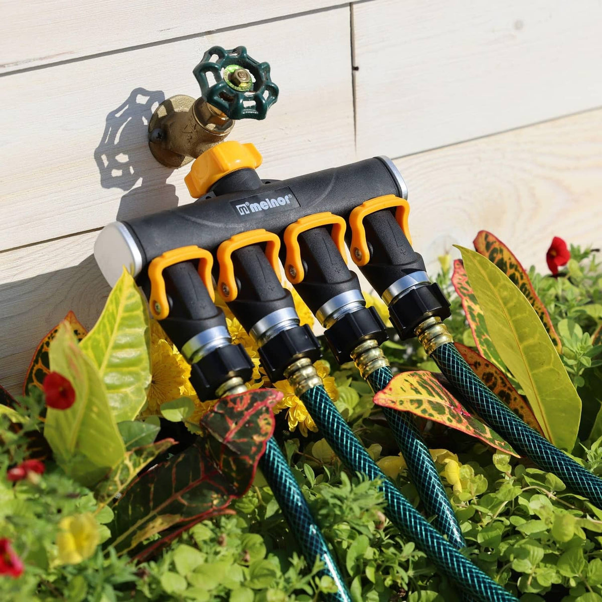 Mounted 4-way lever valve splitter with black body, yellow levers, and attached hoses