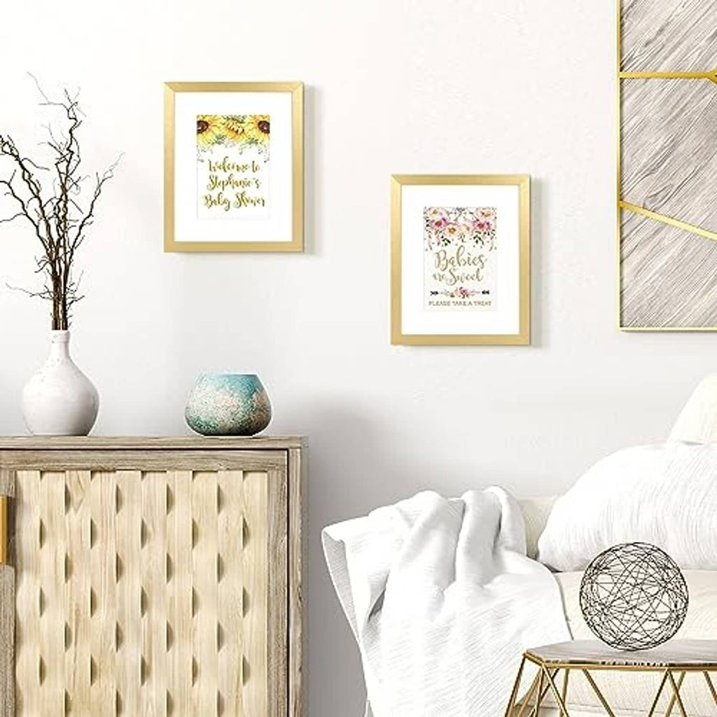 Pair of gold picture frames on a wall, each holding a small printed photo