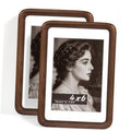 Two walnut wood photo frames with white mats, featuring black-and-white portrait photos