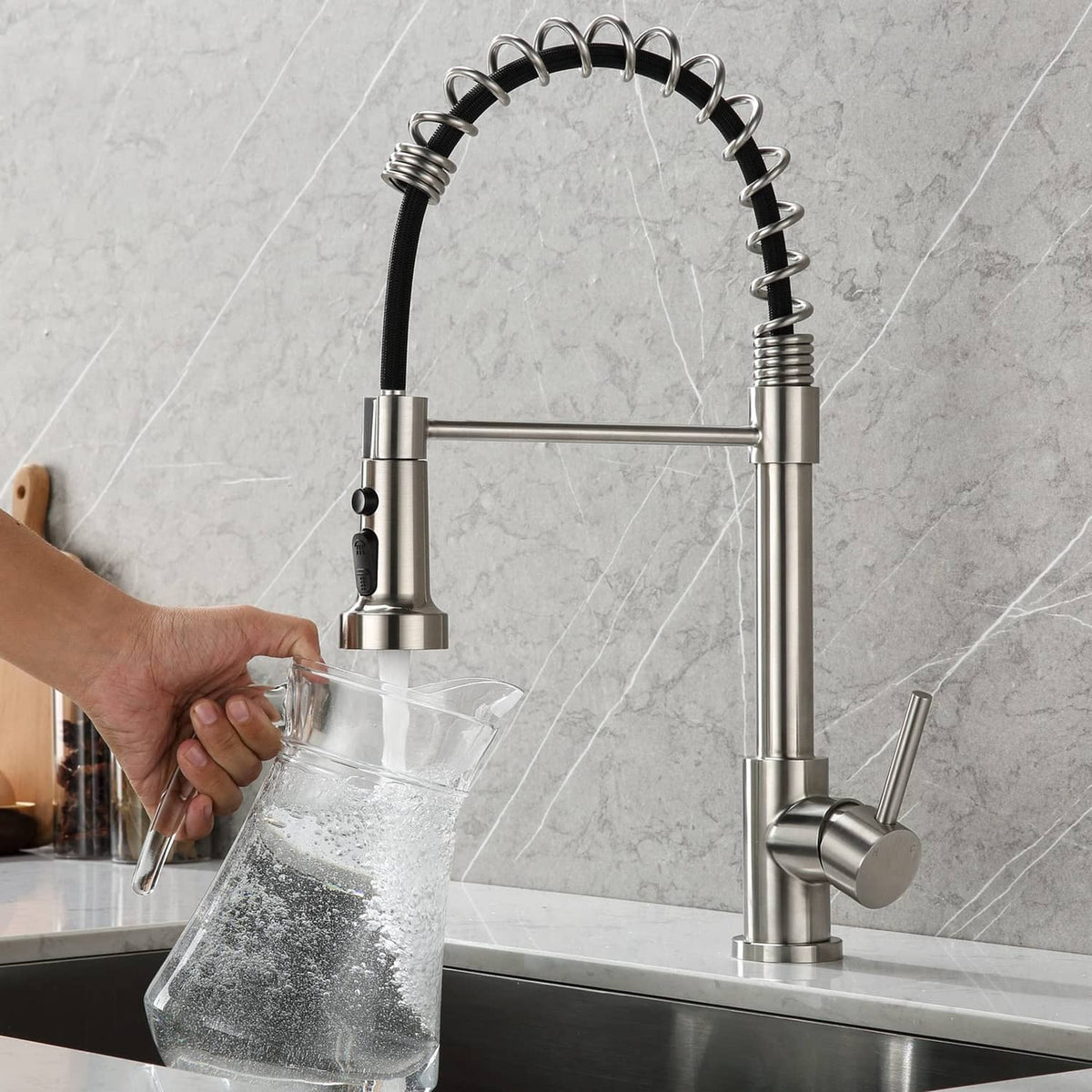 Brushed nickel kitchen faucet sprayer head and hose filling a glass pitcher