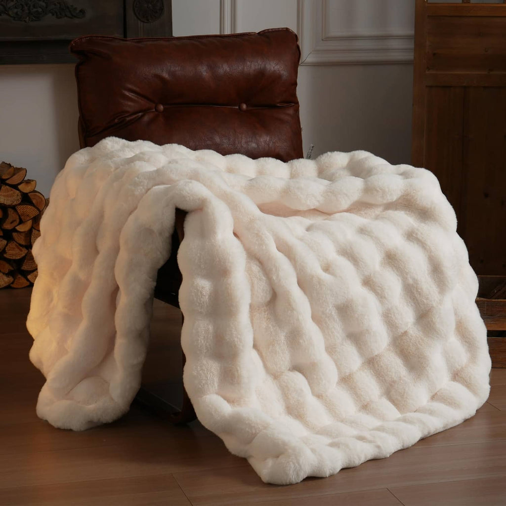 Cream faux fur throw blanket with thick plush loops, draped on a sofa