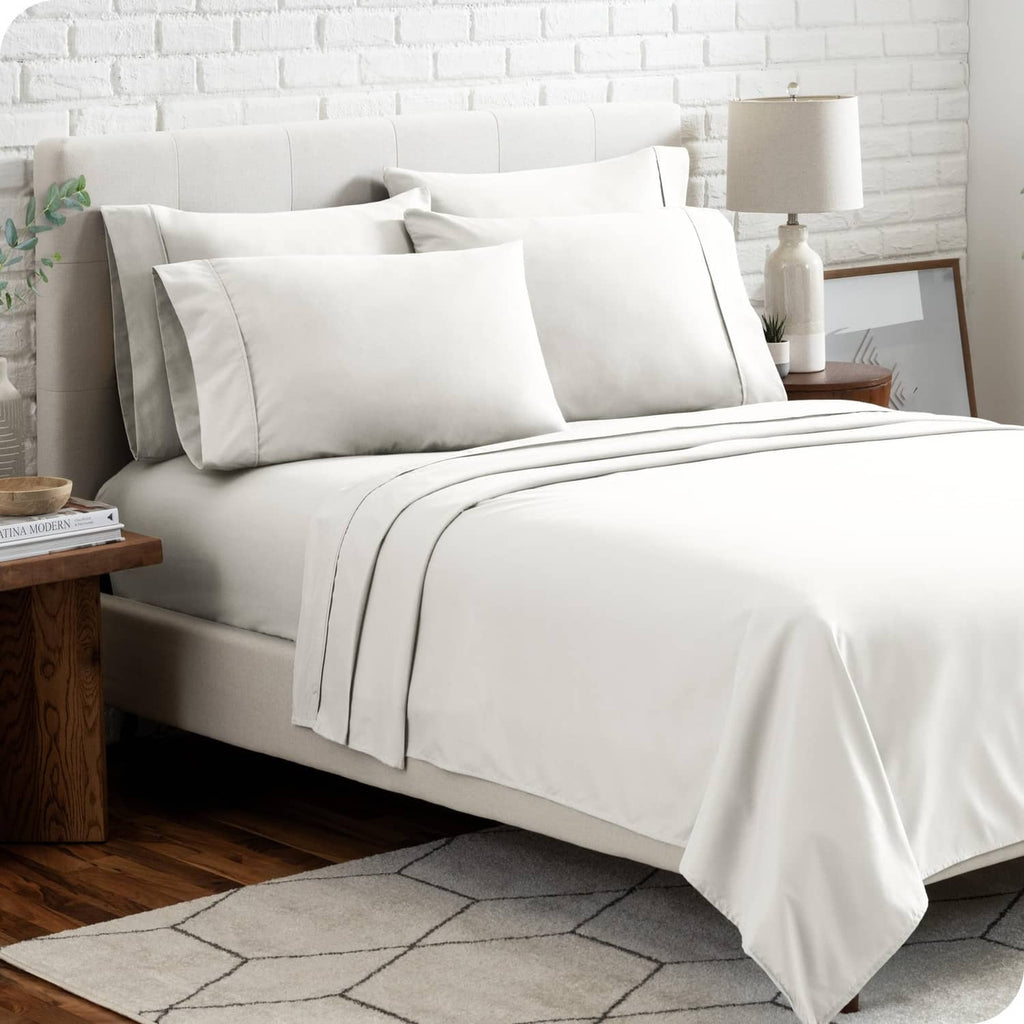 Cream microfiber bedding set on bed with pillows and neatly layered top sheet