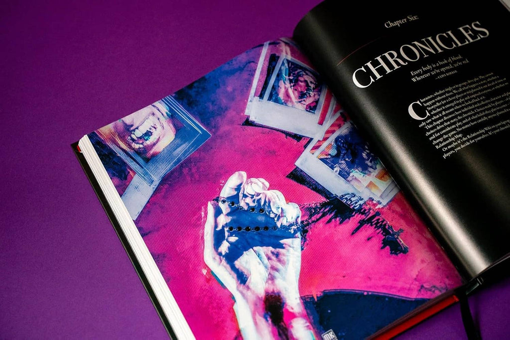 Open hardcover Players Guide spread with pink illustration and black right-page text