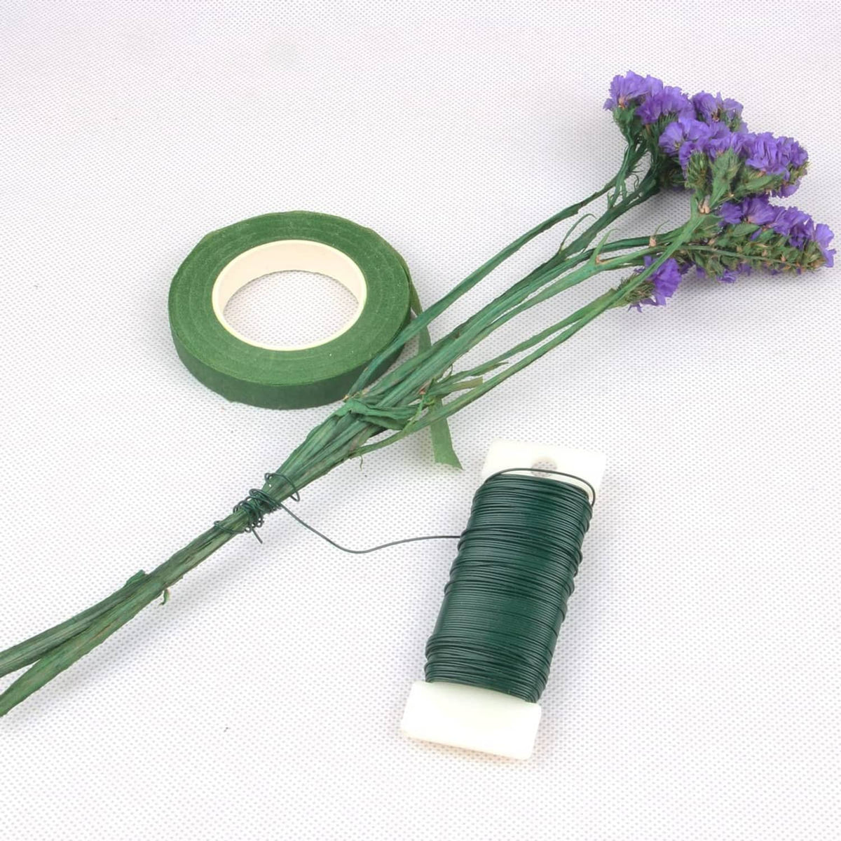 Green floral wire spool with roll tape, plus loose wire strands and small craft flowers