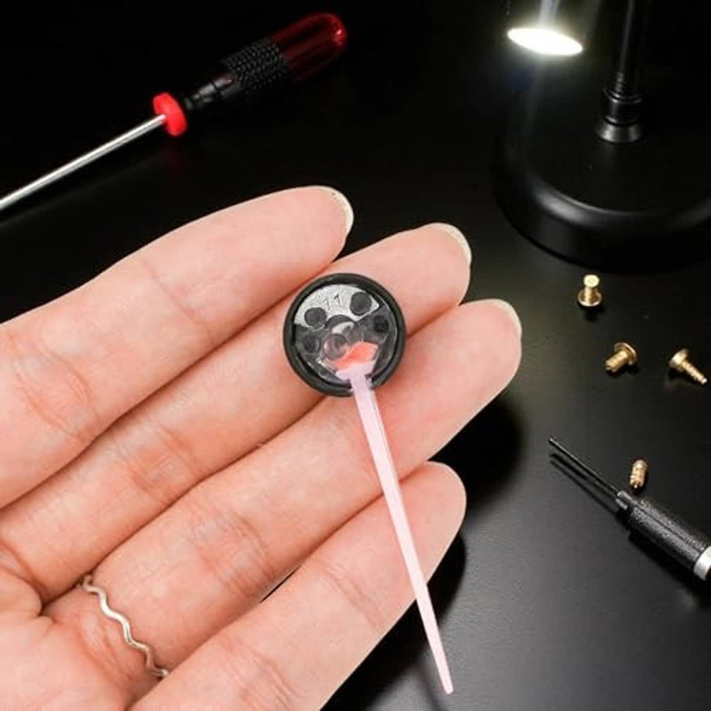 Speedometer needle on black base with white pointer, held in a person’s hand.