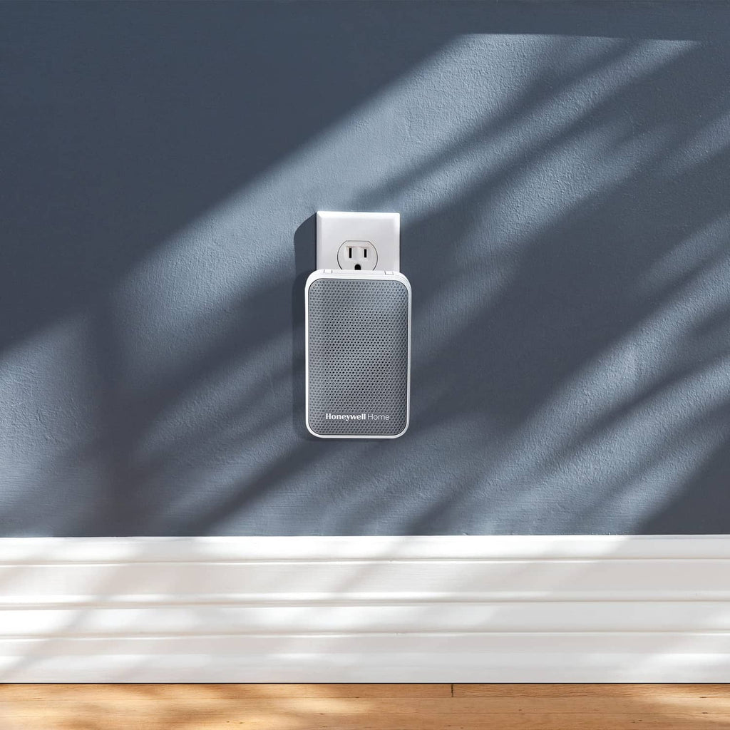 White plug-in doorbell chime plugged into outlet on dark blue wall
