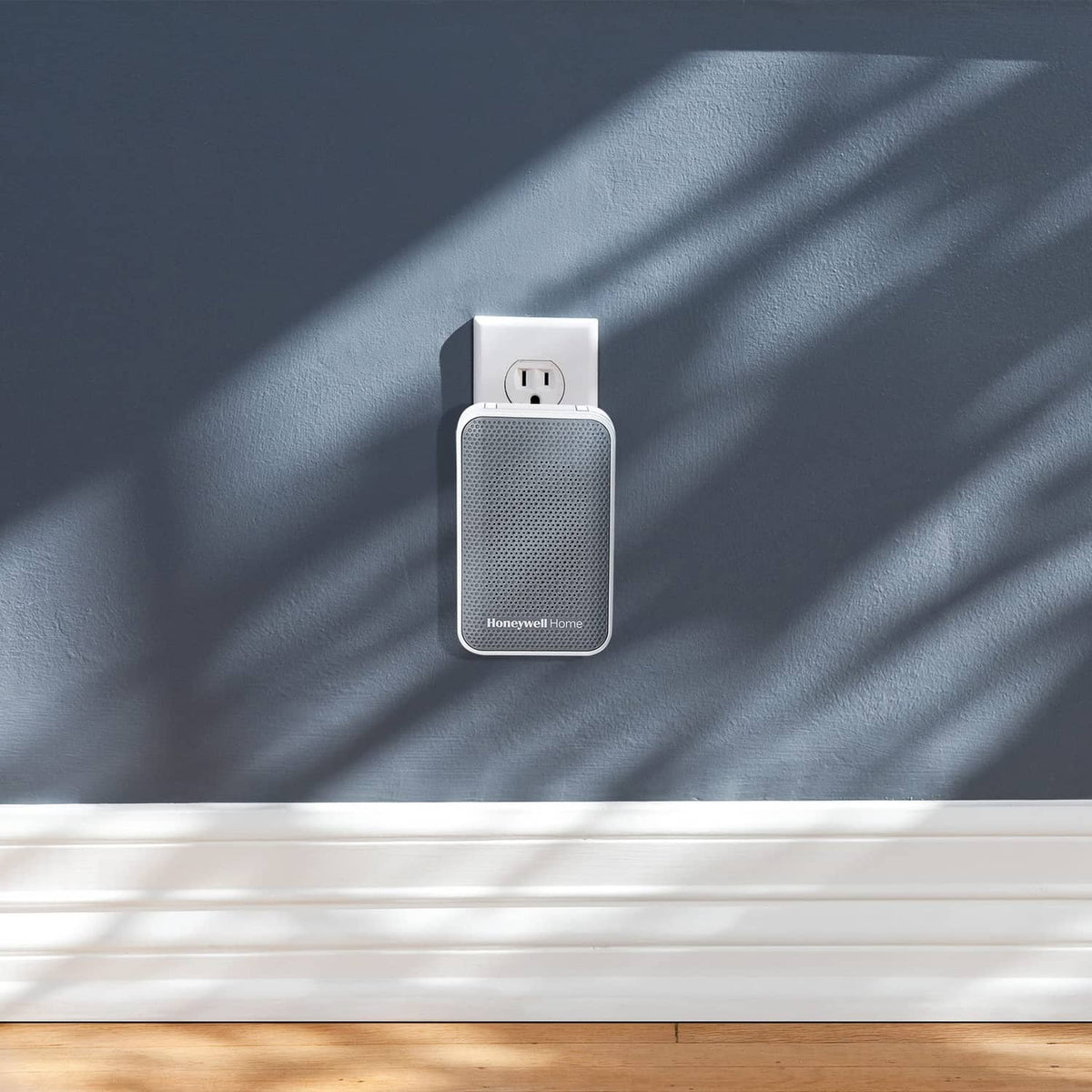White plug-in doorbell chime plugged into outlet on dark blue wall