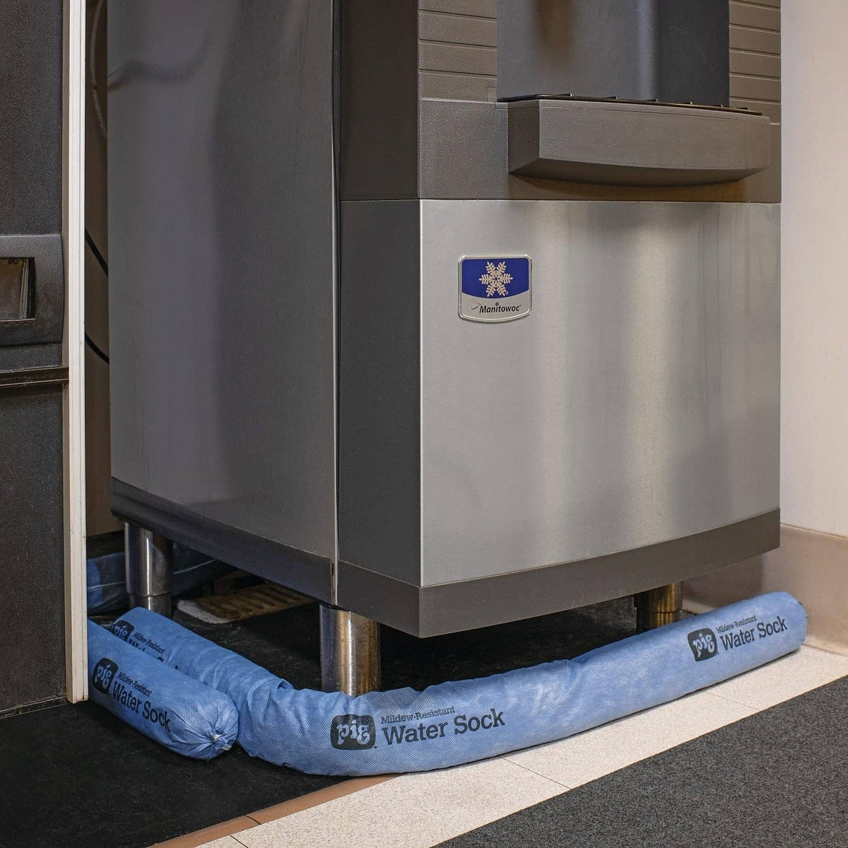 Blue water absorbent sock barrier positioned at the base of a stainless unit