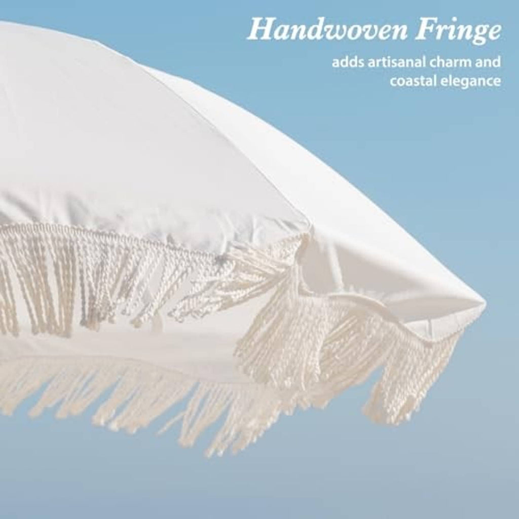 Outdoor patio umbrella canopy edge with white fringe tassels and layered fabric seam.