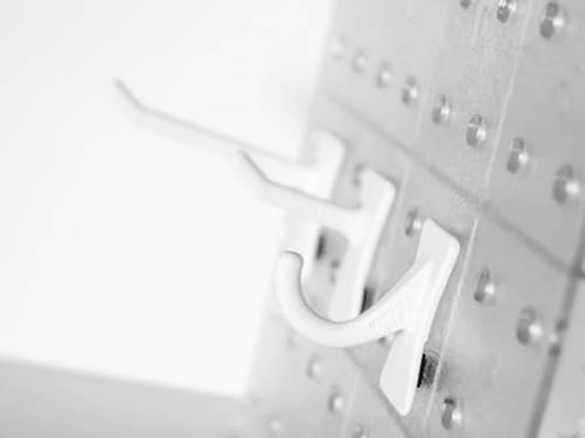 Close-up of a white J-hook snapped into pegboard holes