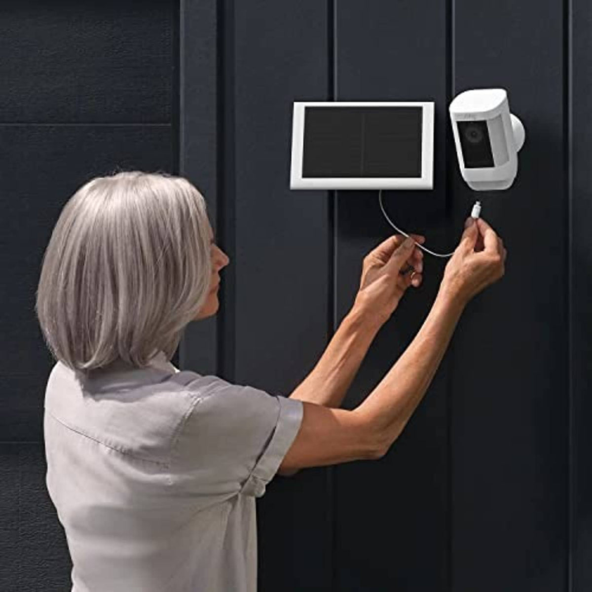 Wall-mounted solar panel and white cable connected to a security camera unit