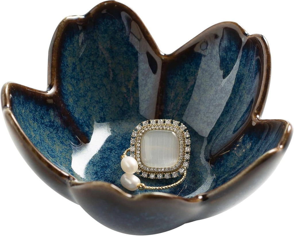 Close-up view of blue ceramic flower jewelry tray with jeweled ring and pearl