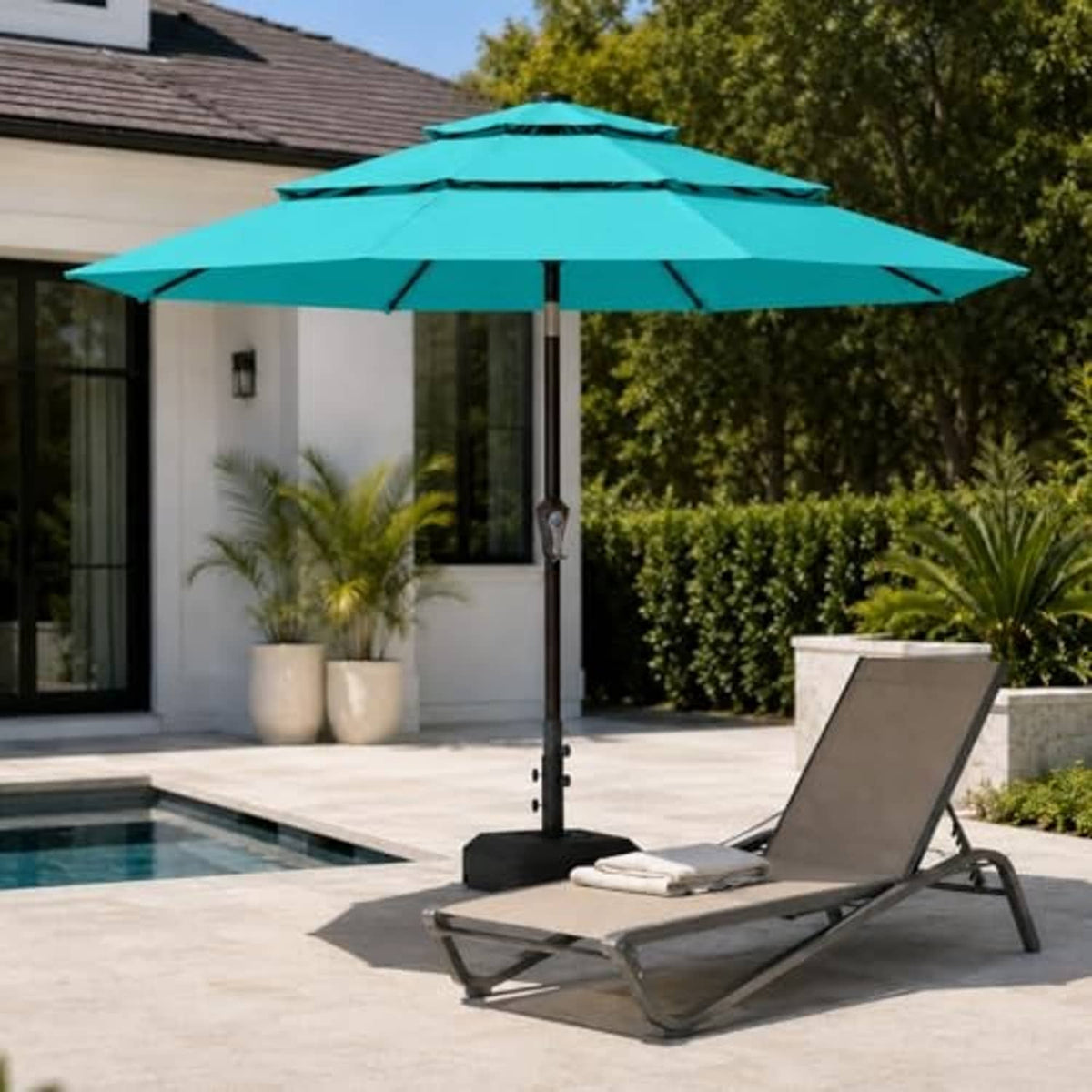 Turquoise 3-tier patio umbrella with vented canopy above outdoor lounge chairs
