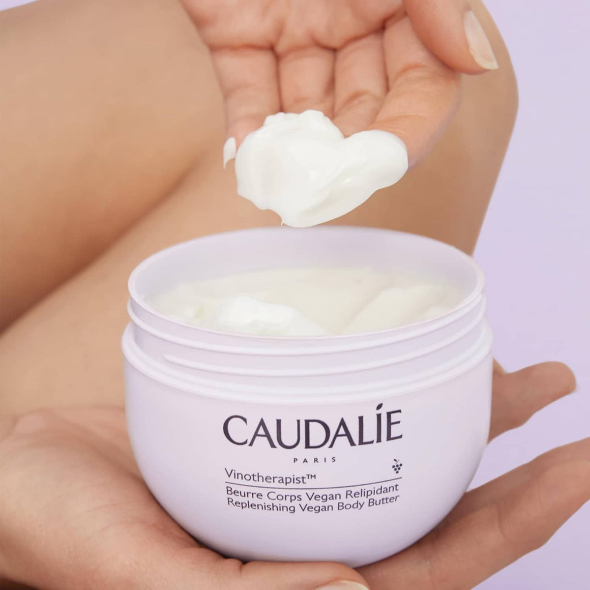 Thick white body butter scoop from CAUDALIE jar, cream on open palm