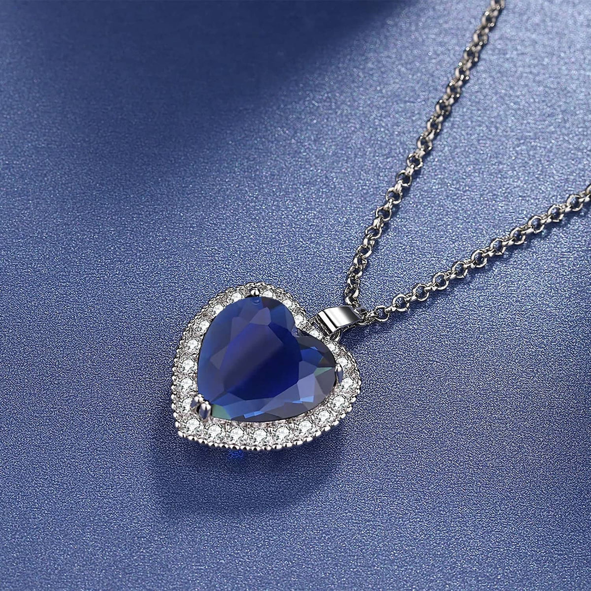 Close-up of silver heart pendant with dark blue faceted gemstone and crystals