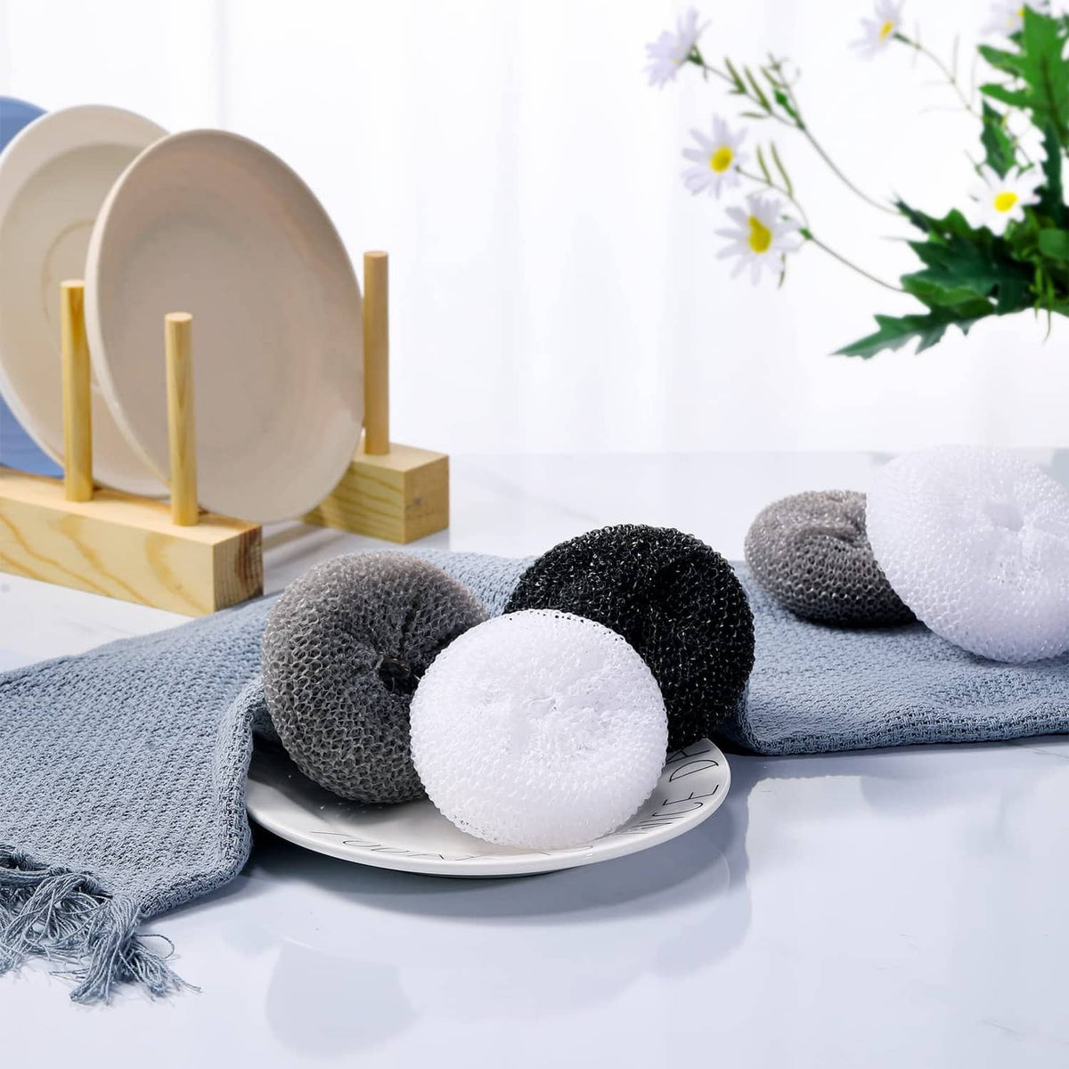 Assorted round nylon dish scrubber pads, white, gray, and black on a plate