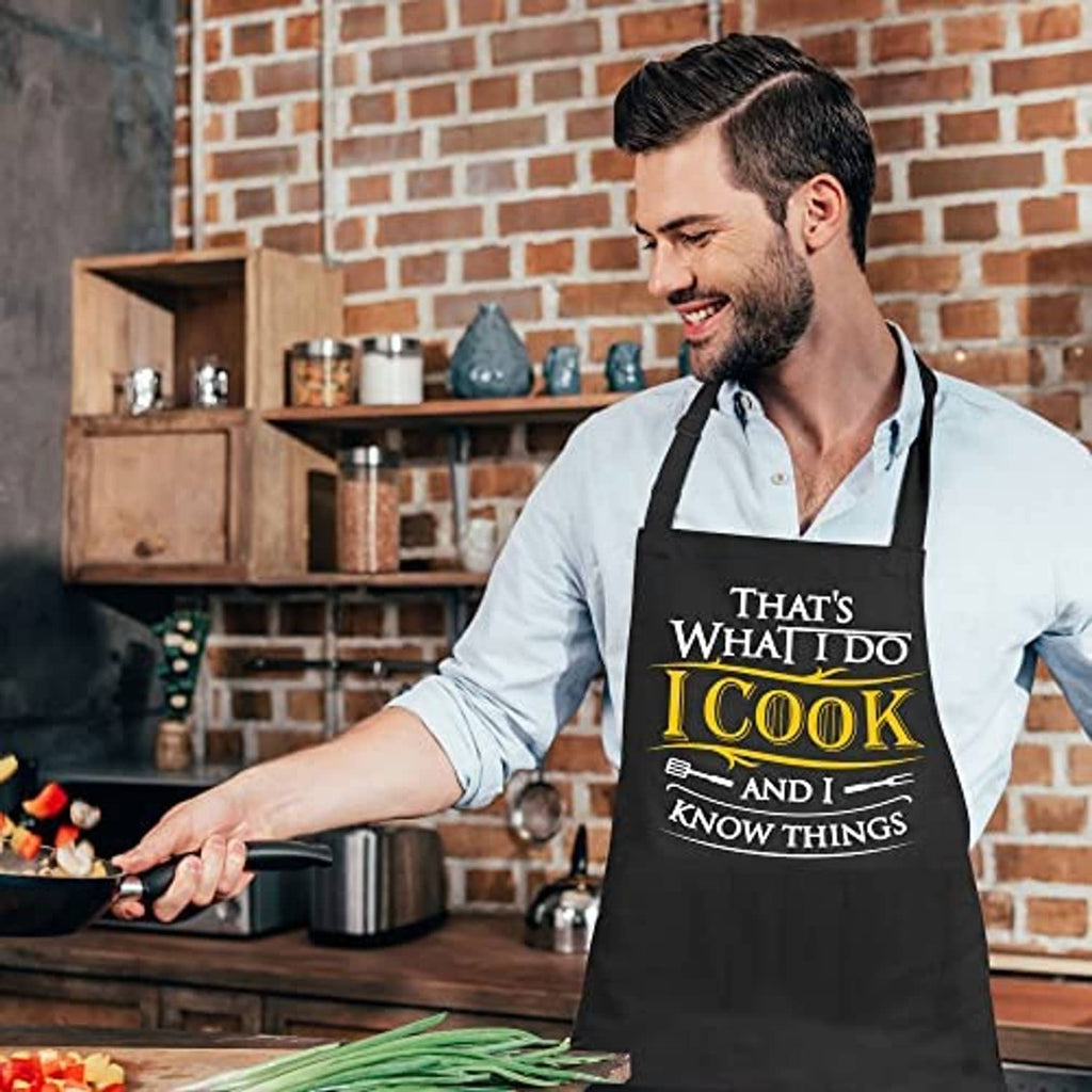 Black chef apron worn by man, featuring 'I Cook and I know things' chest print