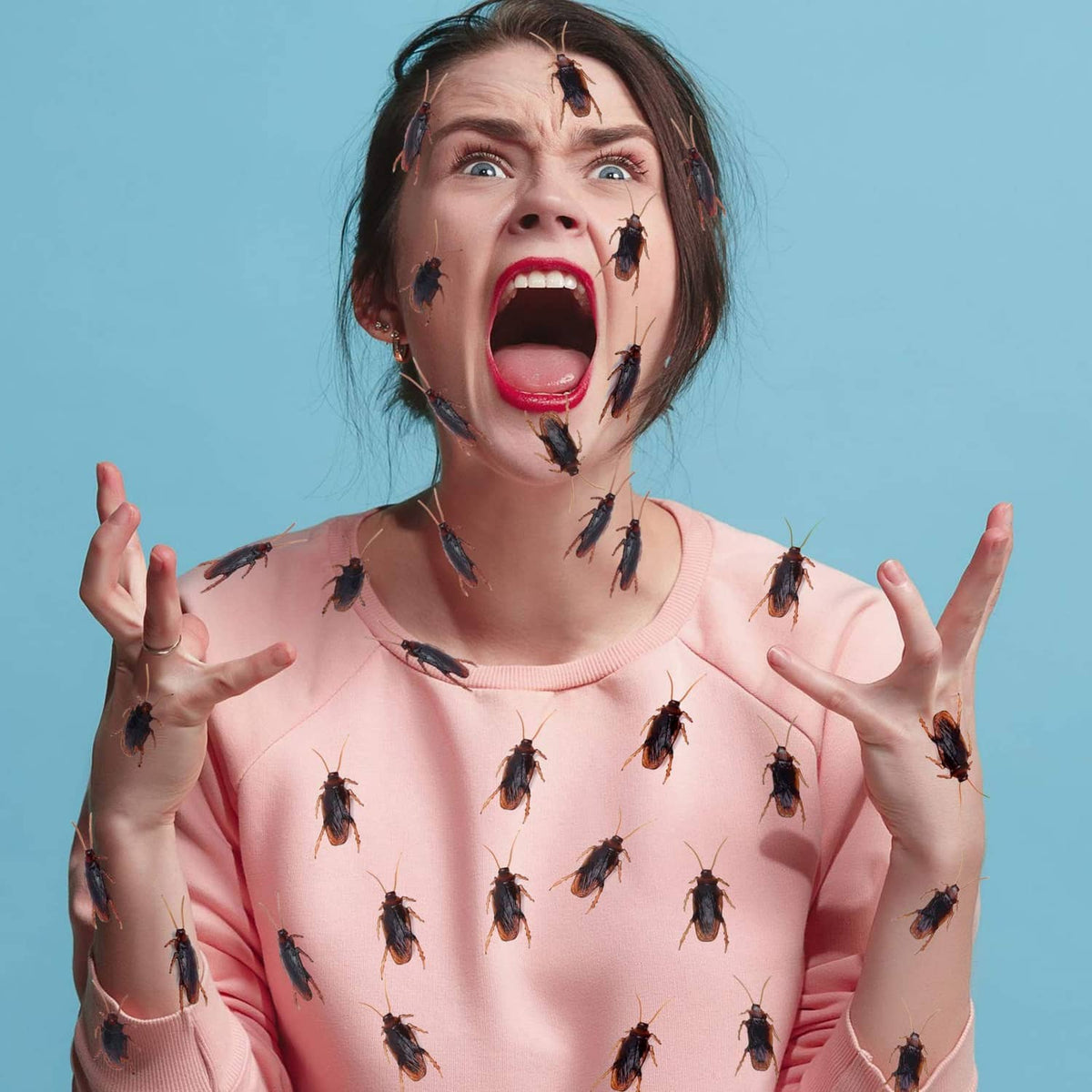 Person wearing fake dark insects on face and pink long-sleeve shirt