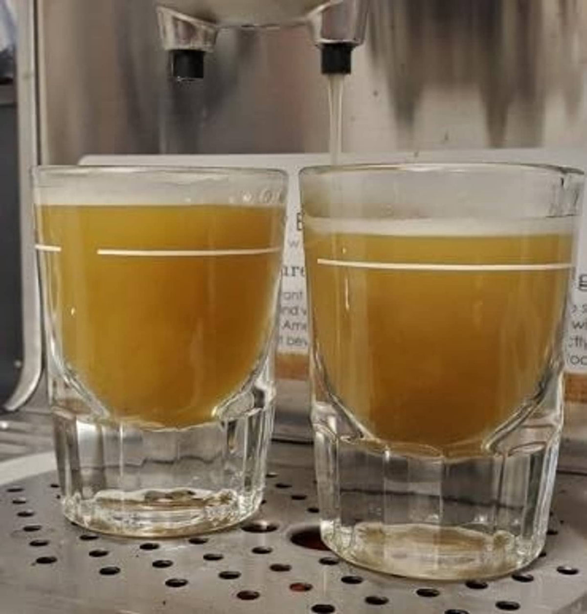 Two clear glasses filled with amber espresso coffee, foam on top