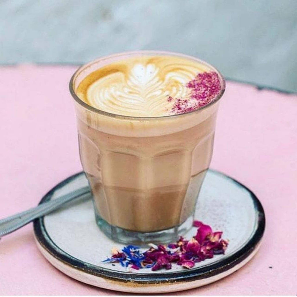 Clear glass tumbler with light coffee drink and whipped foam