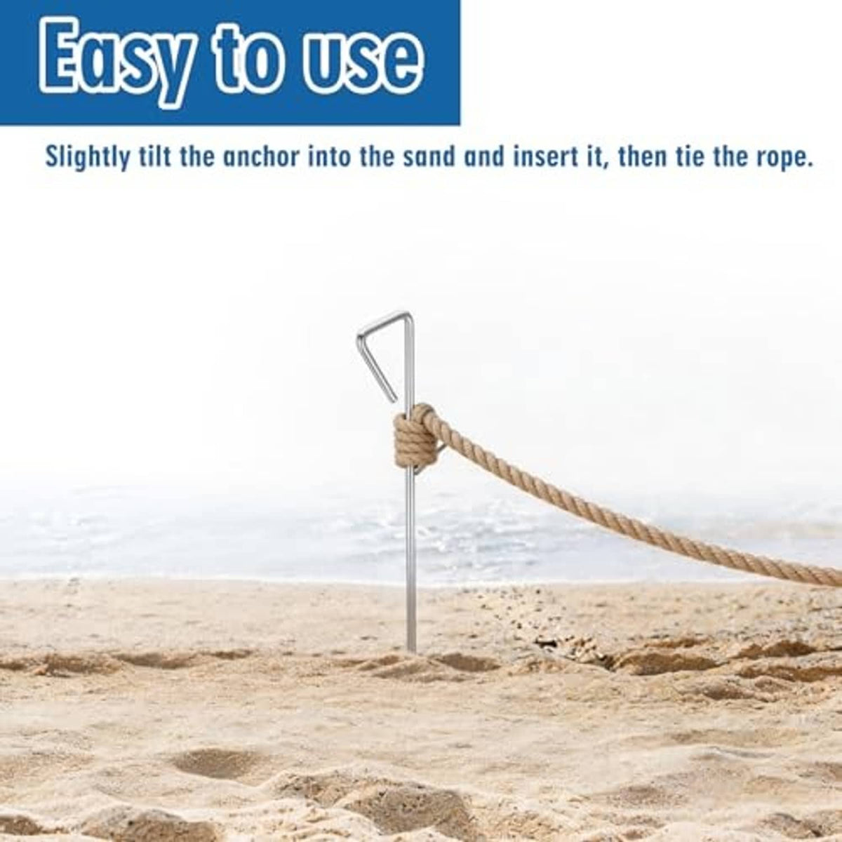 Chrome sand spike anchor with rope tie, held upright in beach sand
