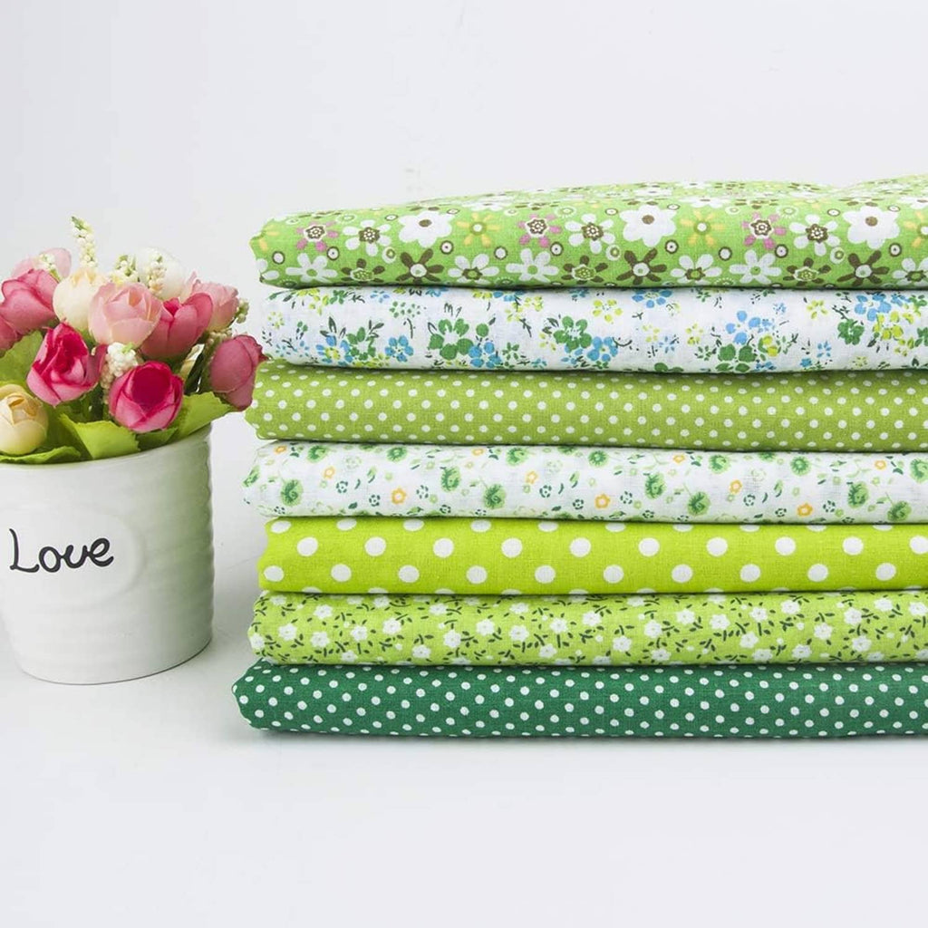 Bundle of folded cotton quilting fabrics with green, blue, and white patterns