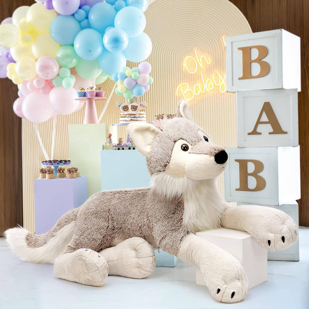 Large gray wolf plush stuffed animal with white muzzle and paws, seated by blocks