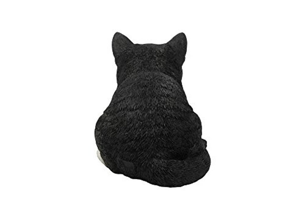 Sleeping cat statue, black with white accents, sitting curled with tail tucked