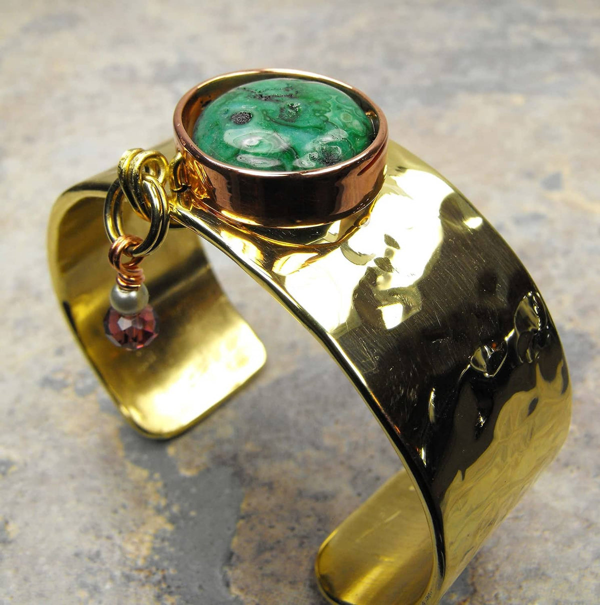 Gold-toned metal bottle with green stone-like cap and pull loop handle