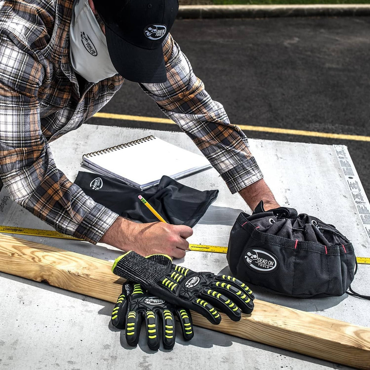 Black tools parachute bag with logo, holding gloves and hand tools on a workbench