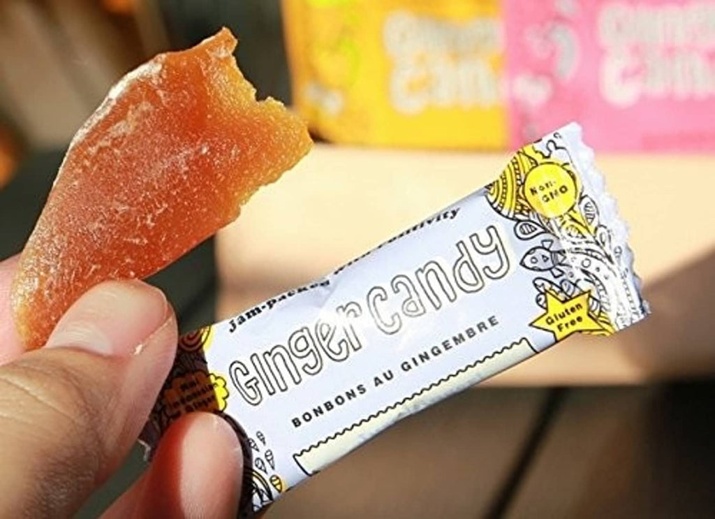 Hand holding a wrapped lemon ginger candy, foil wrapper with text
