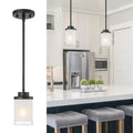 Matte black pendant light with frosted glass cylinder shade and round ceiling canopy.