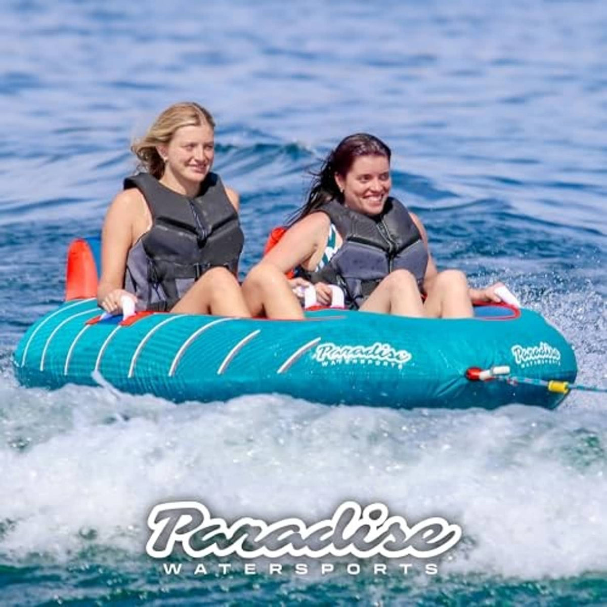 Teal towable tube floating on water with two riders wearing life vests