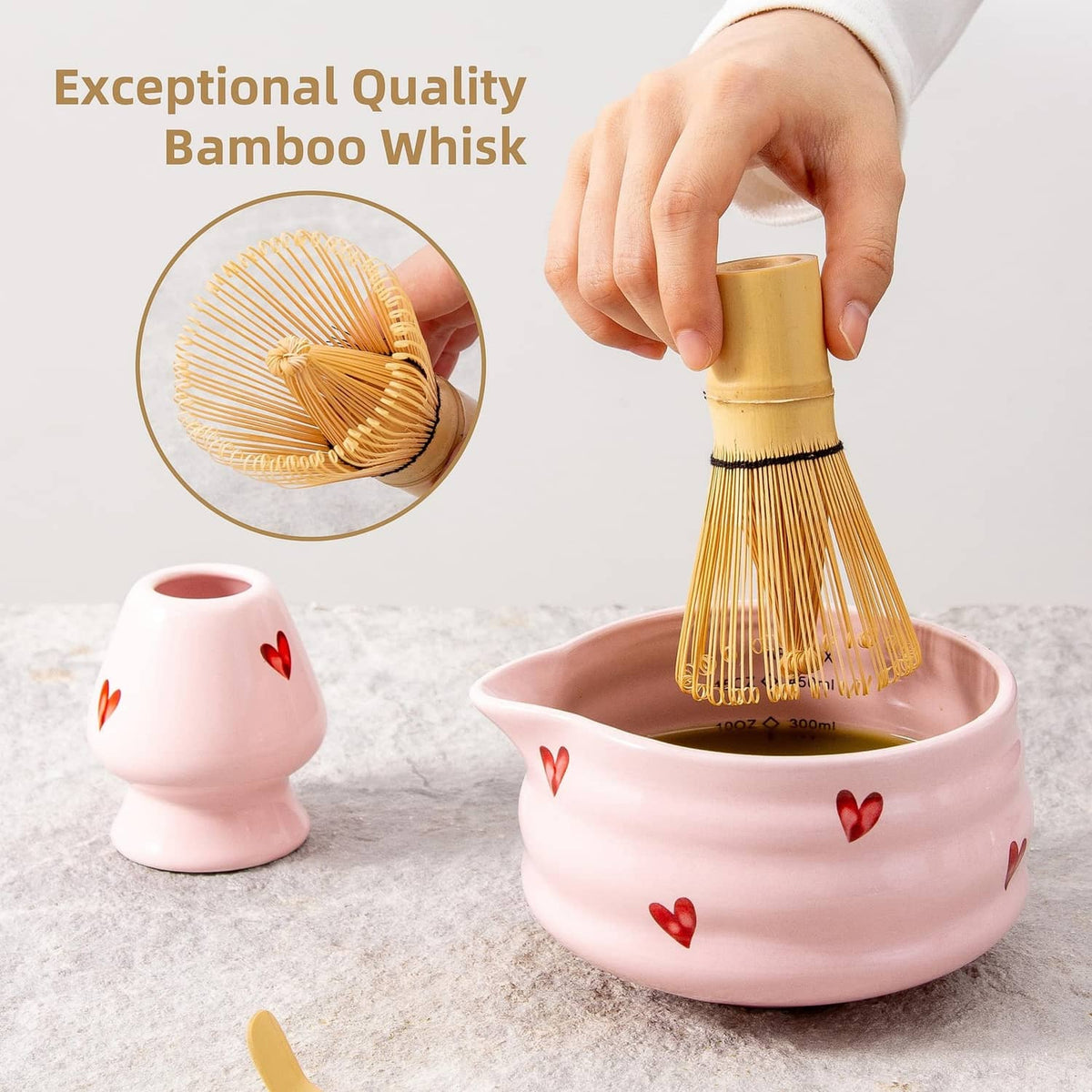 Bamboo matcha whisk held above pink ceramic bowl with heart details