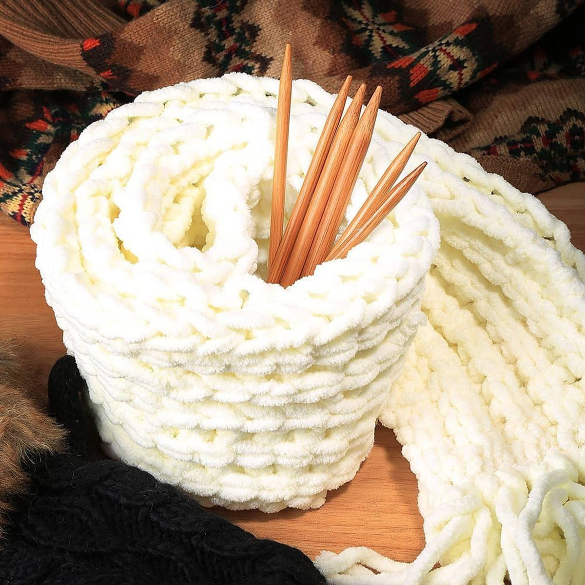 Double-pointed bamboo knitting needles placed on white yarn and knit fabric