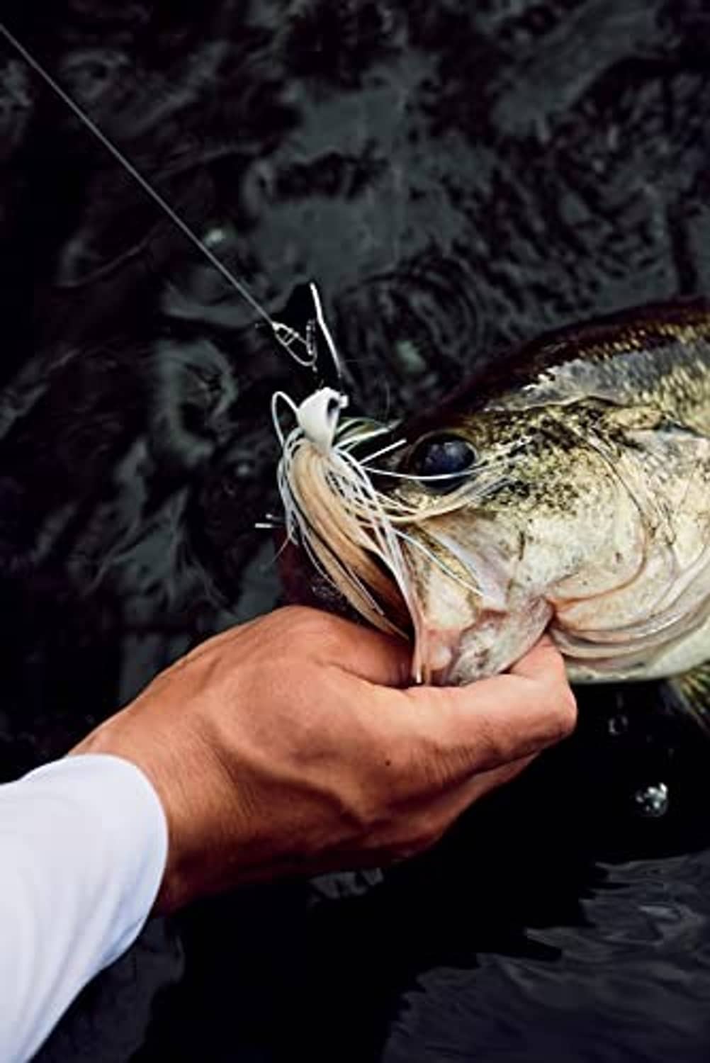 Bladed fishing jig on hook with cream skirt and dark head