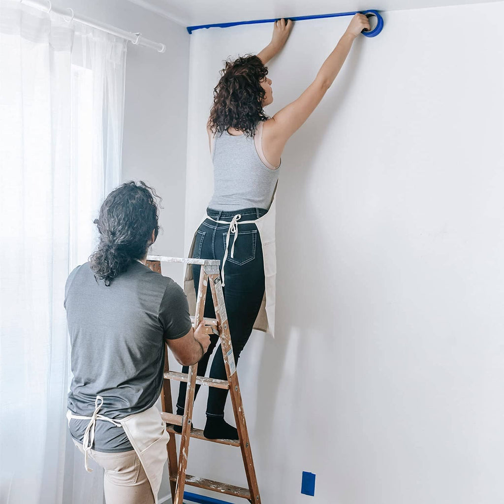 Blue painter’s tape along a wall edge during painting work.