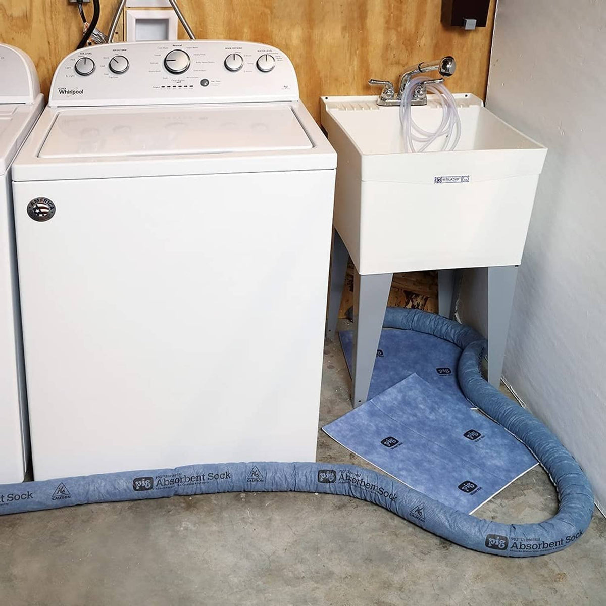 Blue absorbent sock barrier laid along floor beside a utility sink