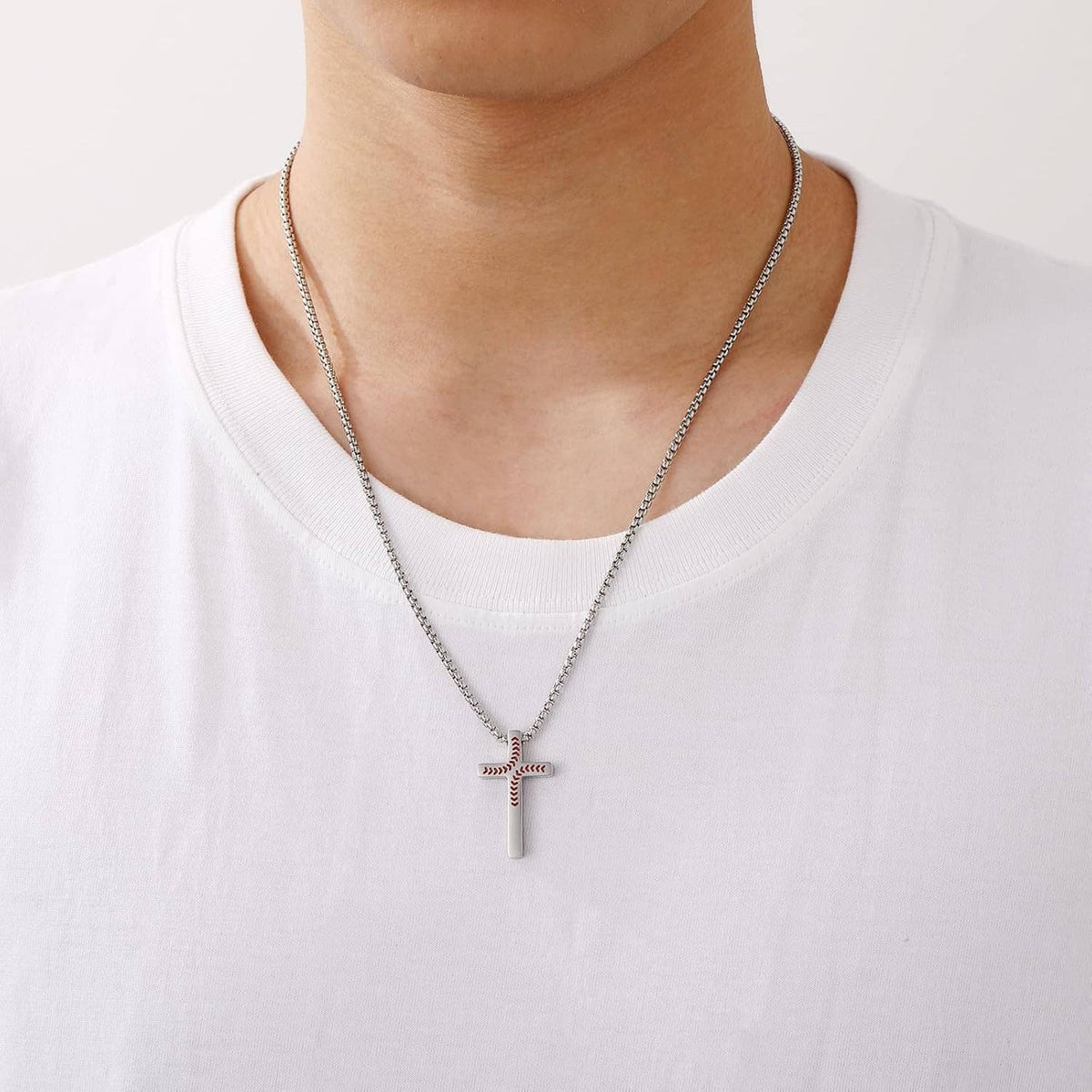 Silver chain baseball cross pendant necklace worn on a white crew neck shirt