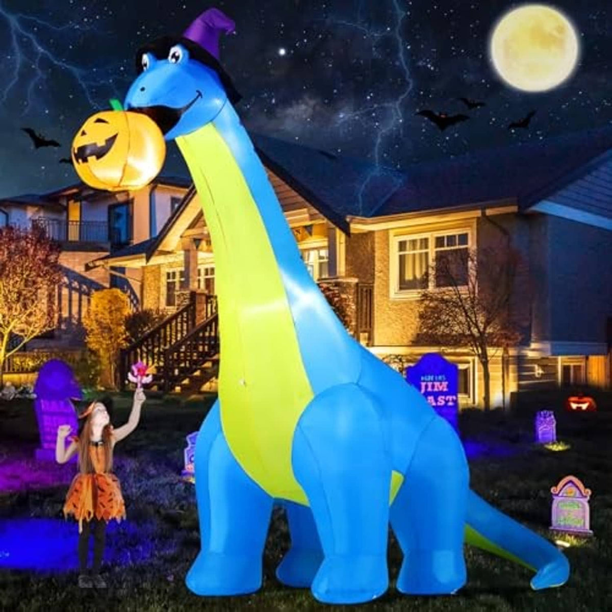 Inflatable blue dinosaur with green stripe, purple hat, holding pumpkin, three-quarter view