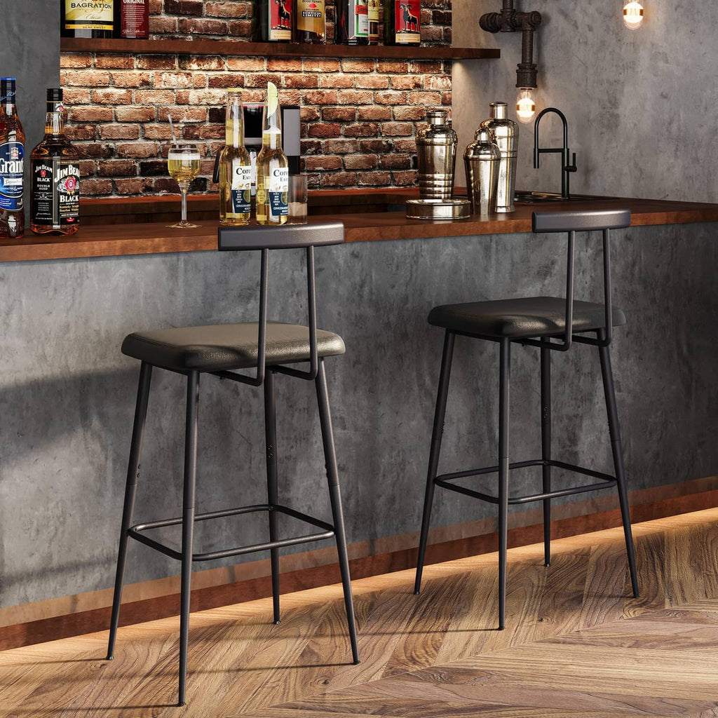 Two black bar stools with cushioned seats, metal footrests, and slender legs