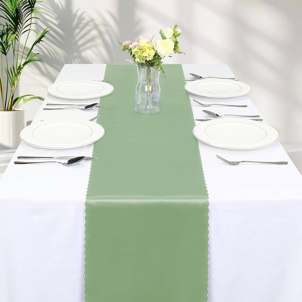 Sage green satin table runner centered on a dining table with white plates