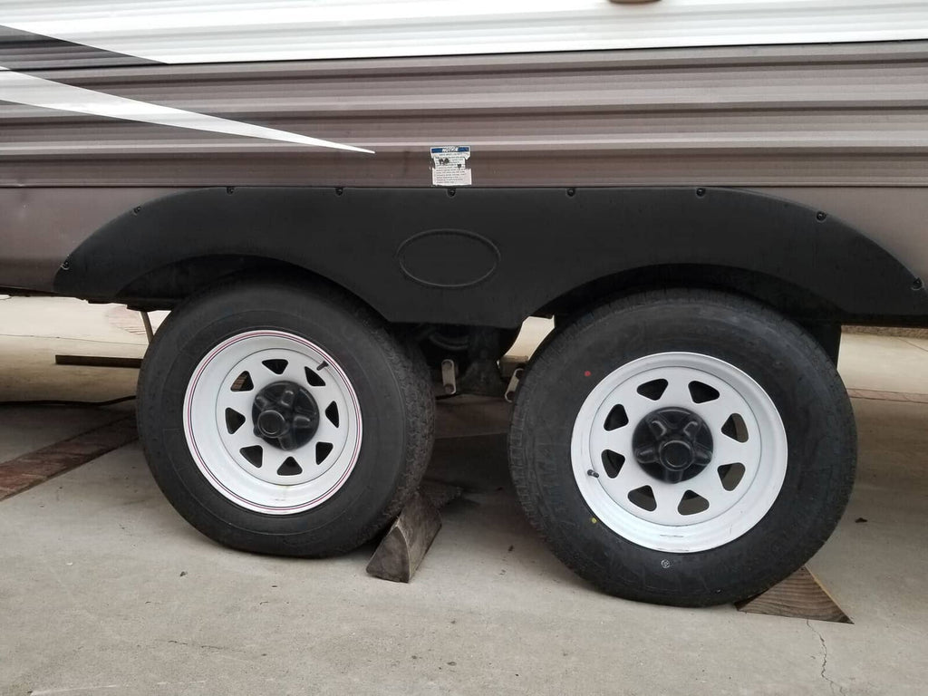 Black tandem wheel fender skirt installed on trailer, molded cover with oval emblem