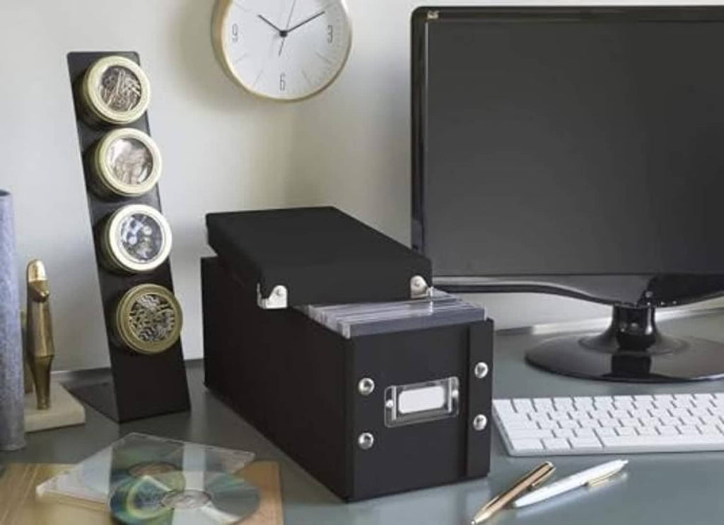 Black CD storage case with open lid on desk, beside an upright CD organizer