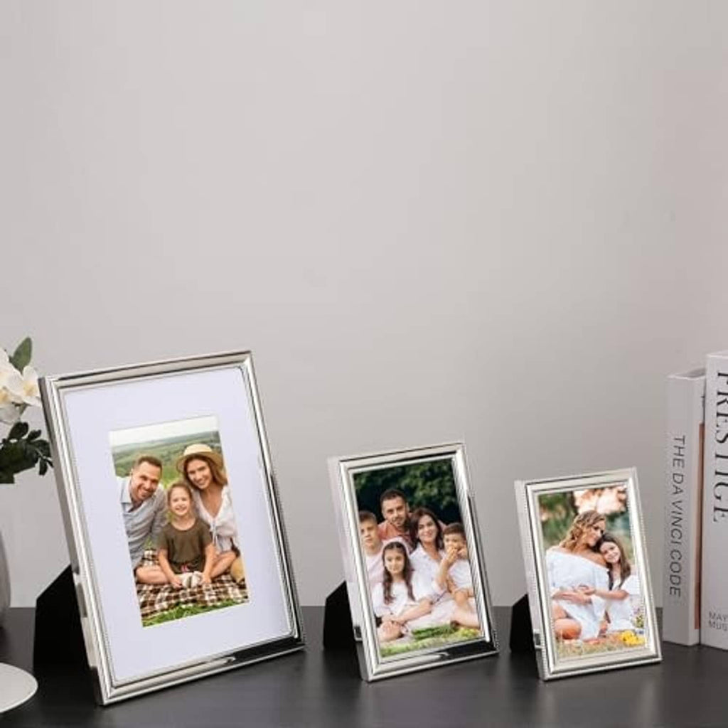 Silver metal picture frame set with three beaded-border frames holding family photos