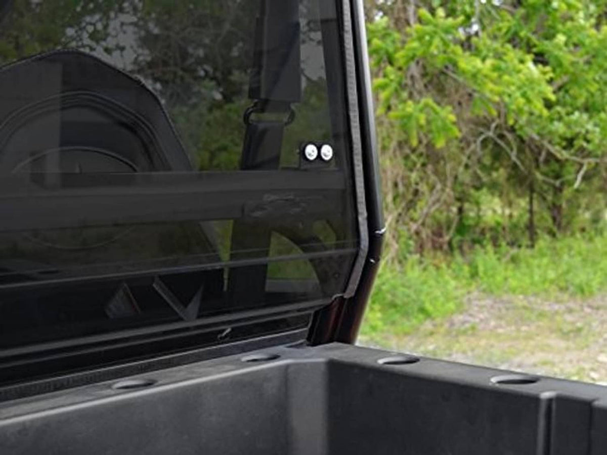 Close-up of dark-tinted rear windshield corner with black frame and mounting points
